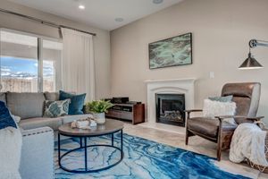 Cozy living room with fireplace, blue area rug, teal accents, and large window with mountain views.