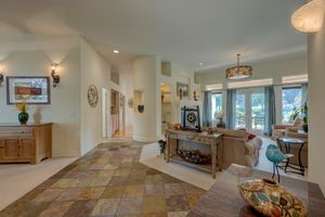 Spacious open-concept living room with stone tile flooring, neutral walls, and French doors.