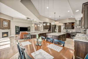 Open-concept dining and kitchen area with a large island, fireplace, recessed lighting, and modern finishes.