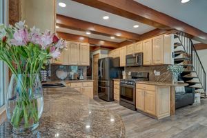 Updated kitchen with light wood cabinets, granite countertops, stainless appliances, and wood beam ceiling.