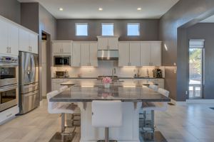 Contemporary kitchen with white cabinets, granite island, stainless steel appliances, and high clerestory windows.