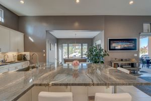 Spacious kitchen with granite countertop island, white cabinetry, and open view to living and dining areas.
