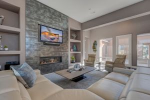 Modern living room with stone accent wall, linear fireplace, built-in shelves, and neutral sectional sofa.