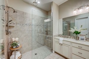 Elegant master bath with walk-in glass shower, tile surround, and double vanity with granite top.