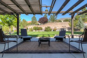 Covered patio with pergola, outdoor seating, fire pit, and scenic mountain landscape views.