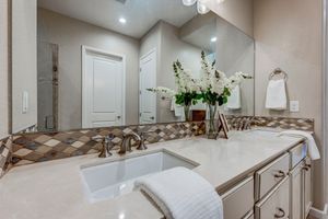 Secondary bathroom vanity with quartz countertop, mosaic backsplash, and undermount sink.