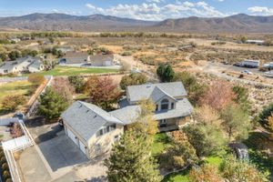 Aerial view of spacious residential property surrounded by trees with mountain range and valley in background.