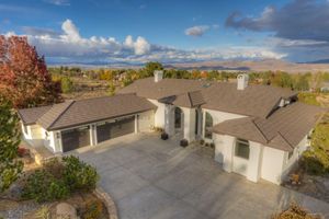 Aerial view of a stucco home with a three-car garage, tile roof, and panoramic mountain views.