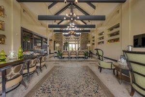 Grand open-concept living space with vaulted ceilings, exposed black beams, chandelier, and built-in shelving.