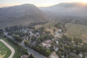 Aerial view of a residential neighborhood nestled at the base of a mountain range at sunset.