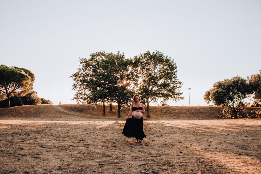 A distant figure in black dress stands on a hill path during golden hour.