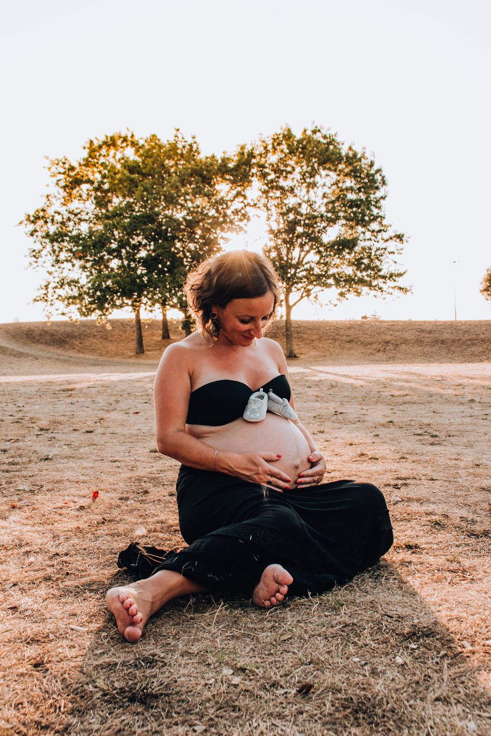 A peaceful moment captured as someone sits cross-legged on dry grass during sunset.