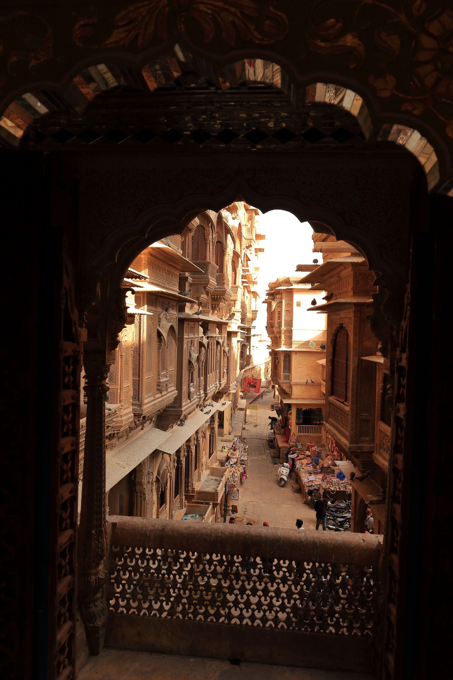 View through stone archway of narrow alley in ancient Indian city architecture.