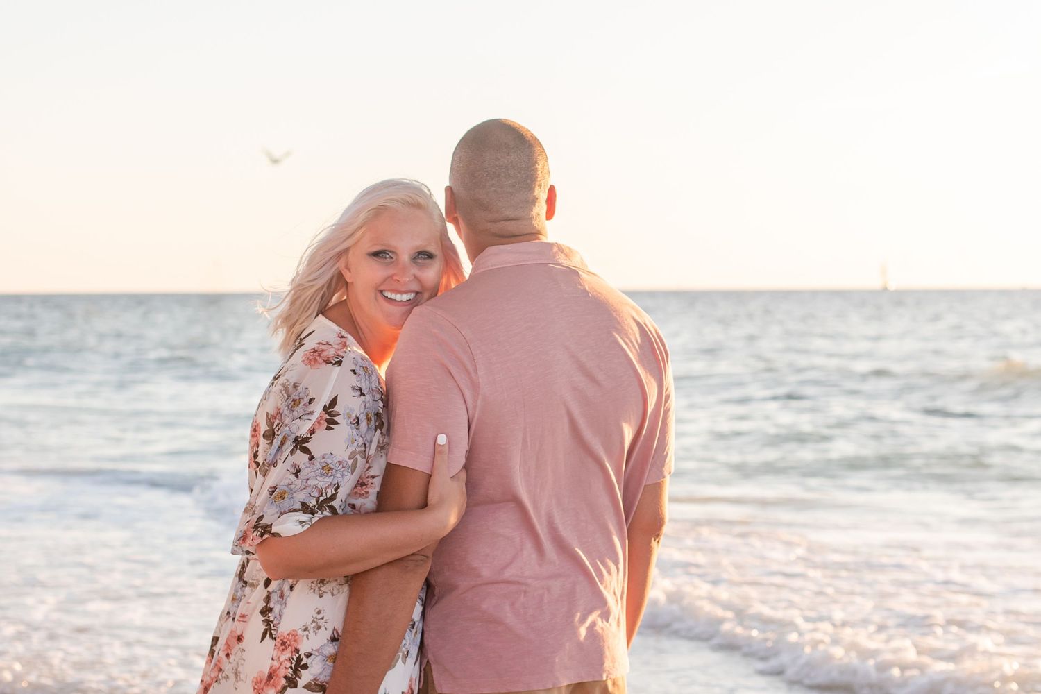 Sunset beach portrait session with couple in pink and floral attire.