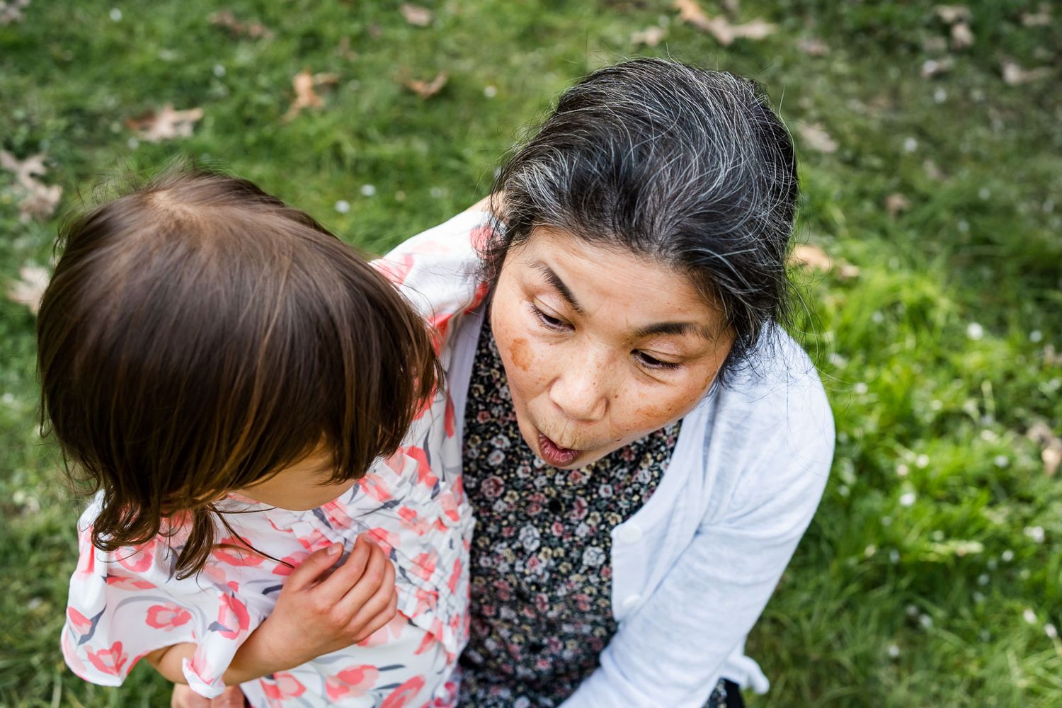 Granddaughter telling grandma a secret on the grass