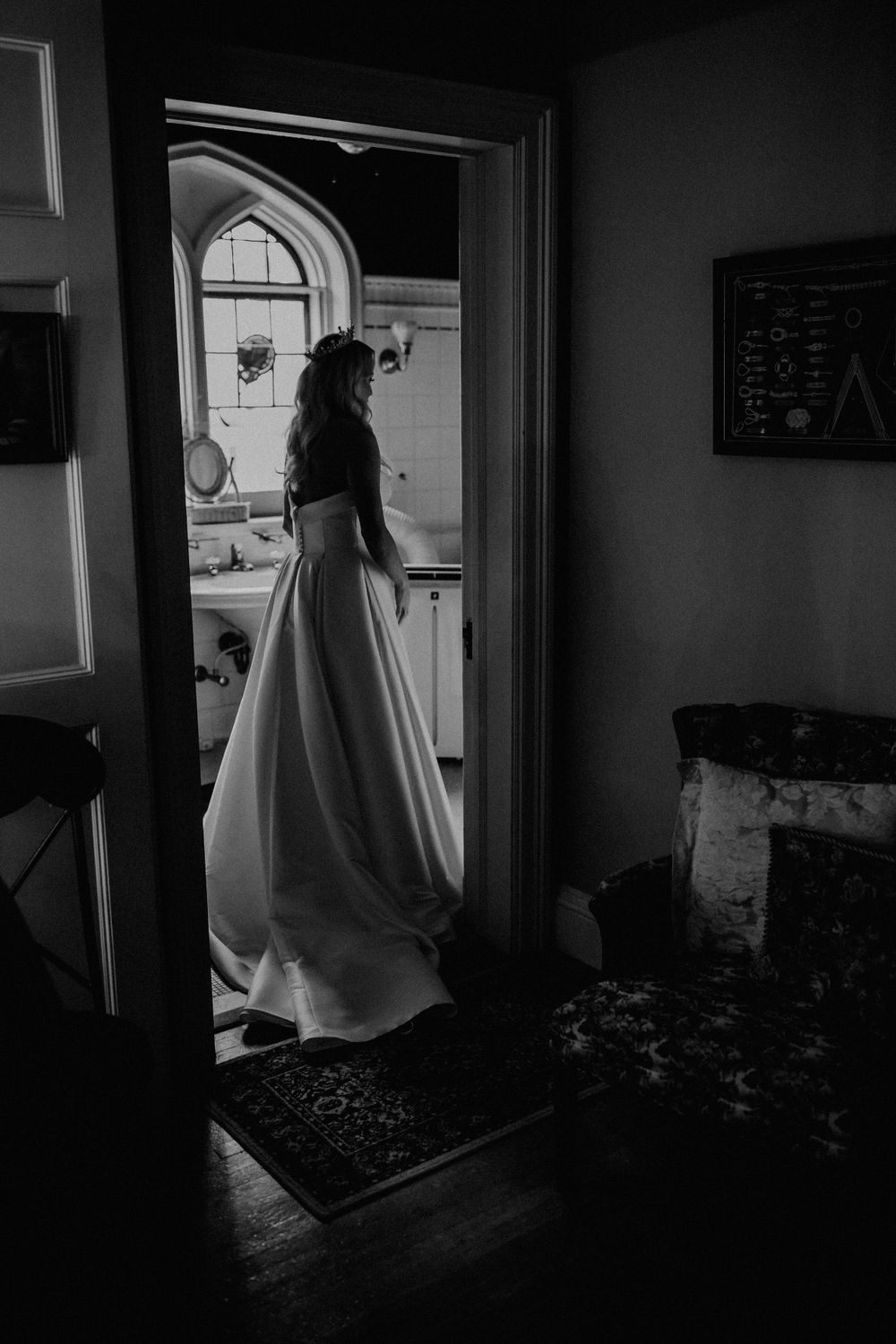 Silhouette of a wedding dress through a doorway in dramatic black and white.