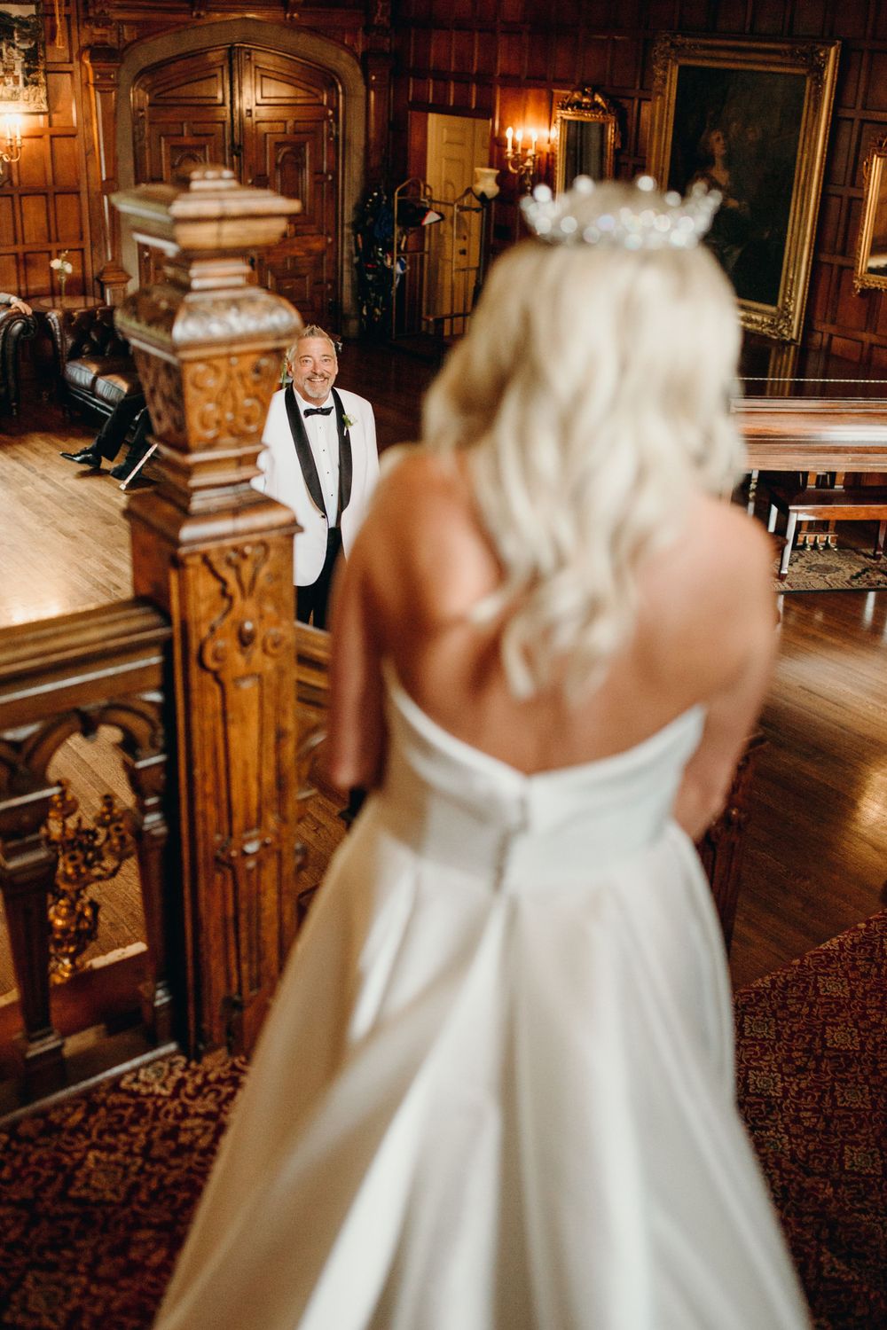 Classic white wedding dress captured on vintage wooden staircase with warm lighting.
