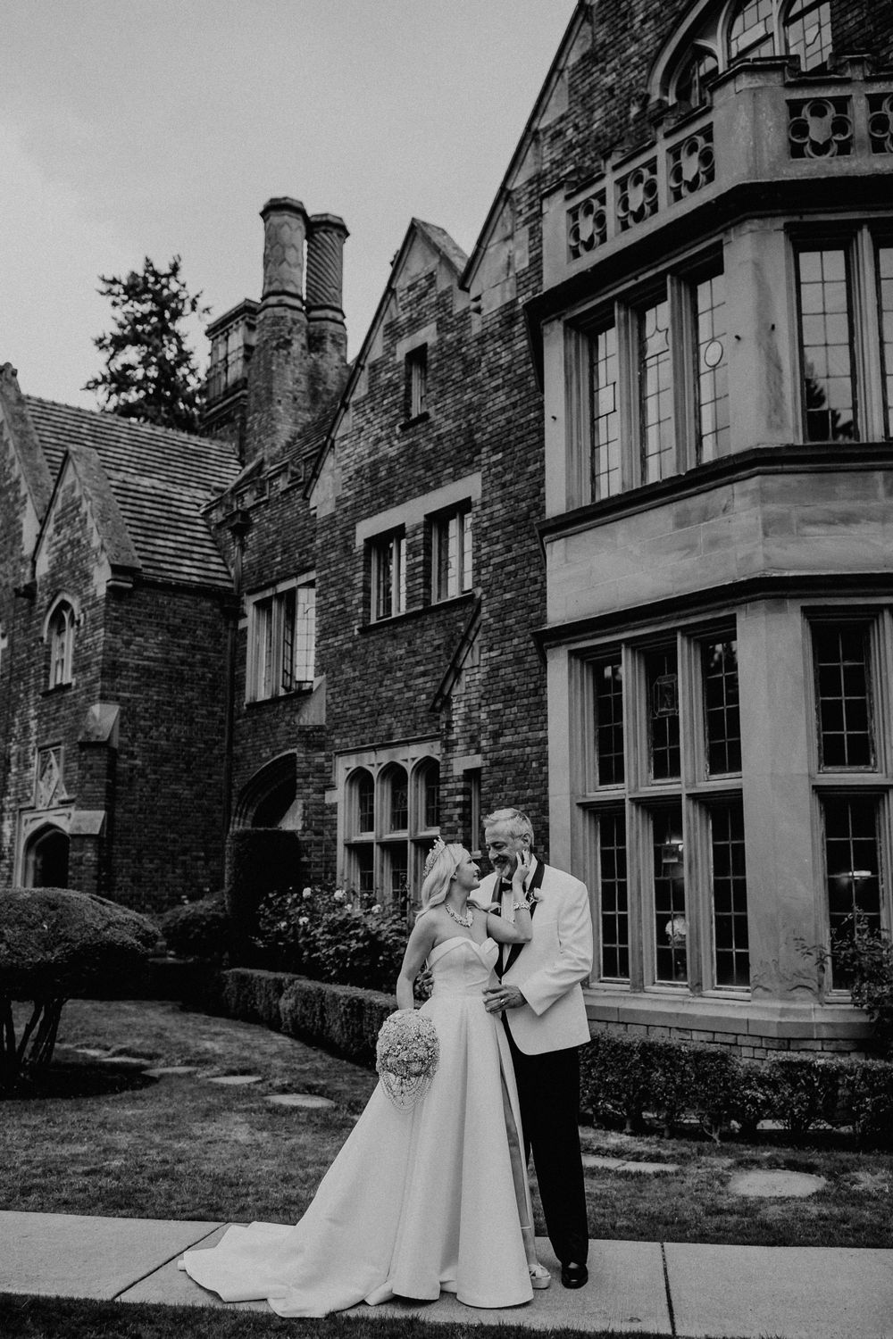 A romantic black and white capture of newlyweds against a Gothic-style architectural backdrop.