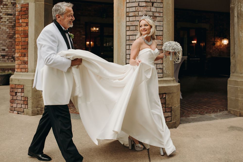 Elegant outdoor wedding photo with white dress flowing in the breeze.