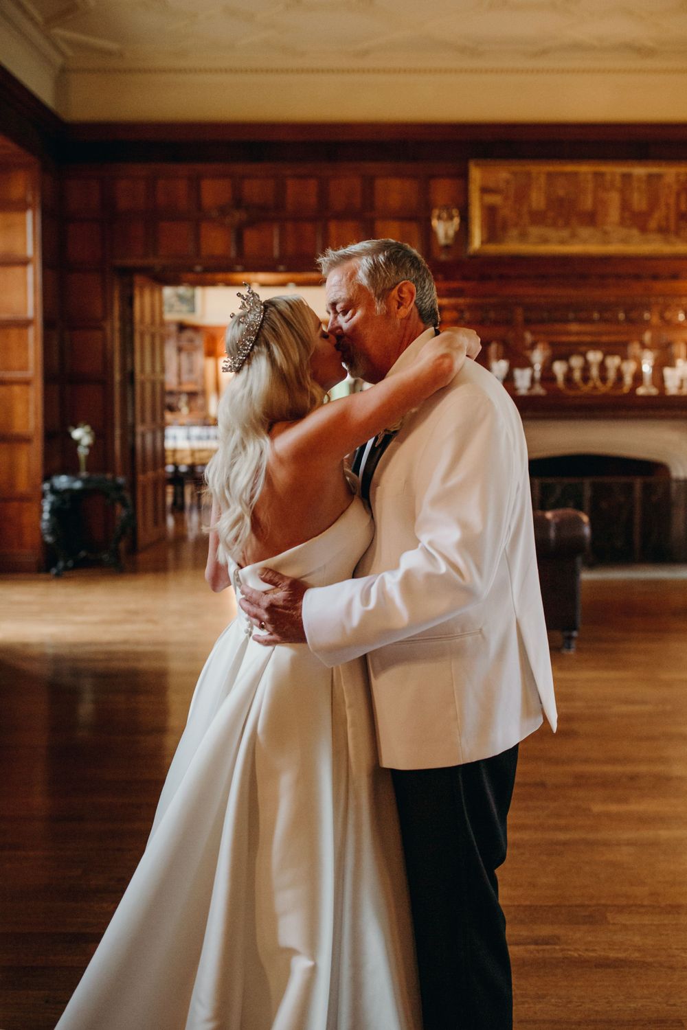 Intimate dance moment captured in warm-toned wedding venue with wooden paneling.
