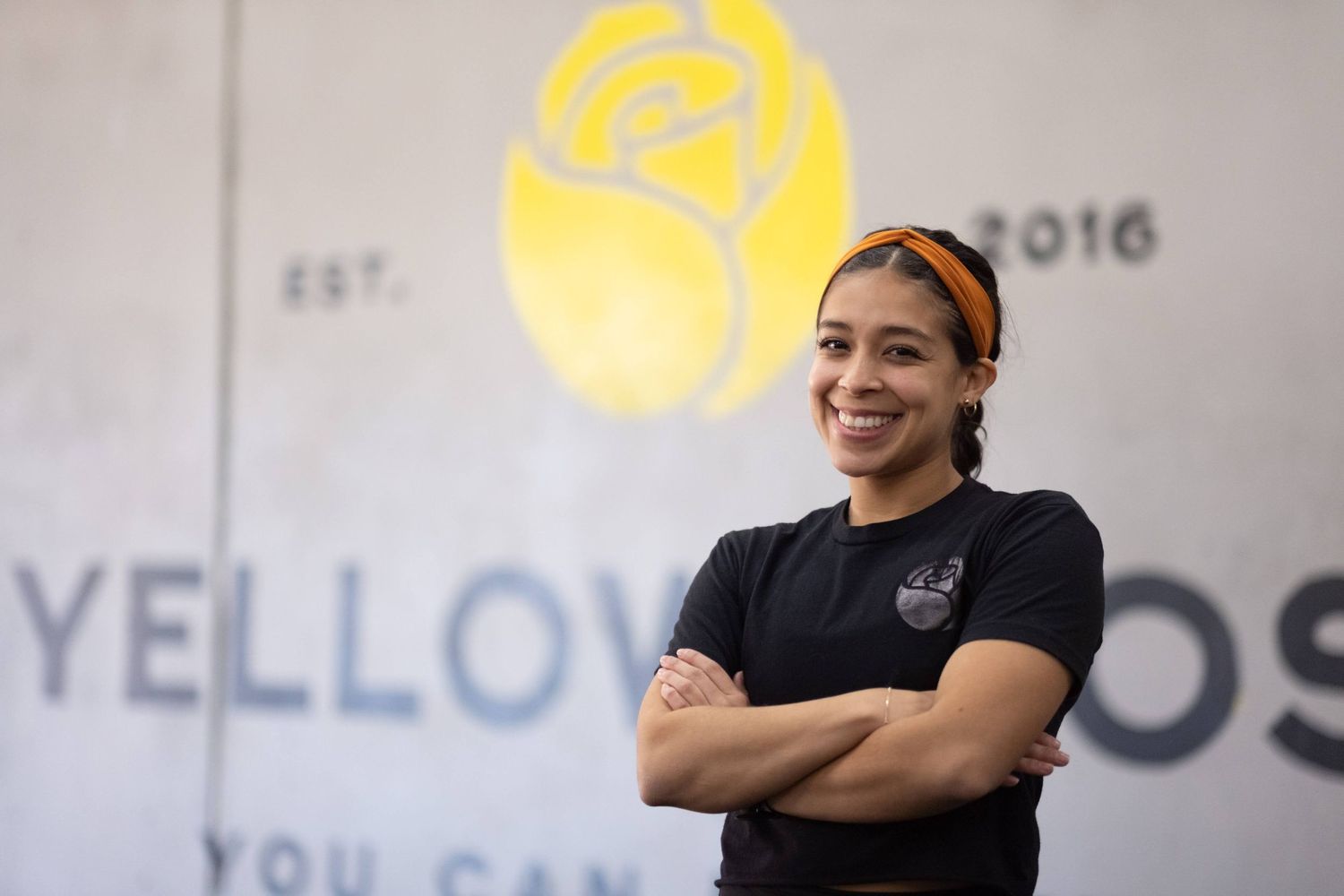 Staff members posing in front of yellow business logo signage.