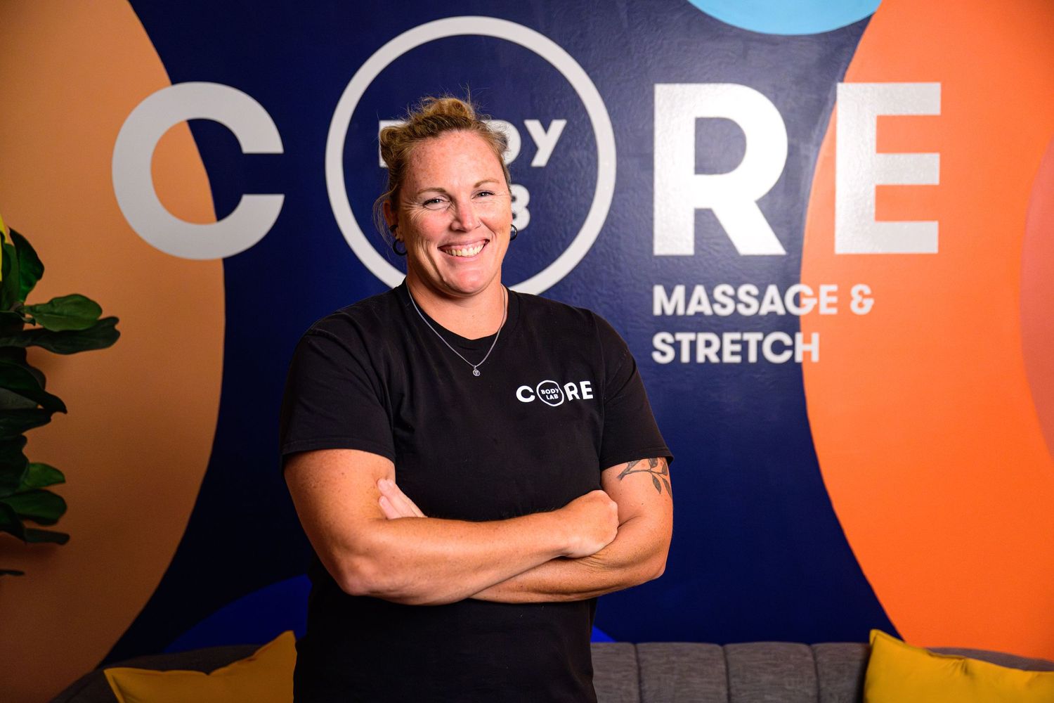 Fitness trainers posing against colorful branded backdrop in black uniforms.