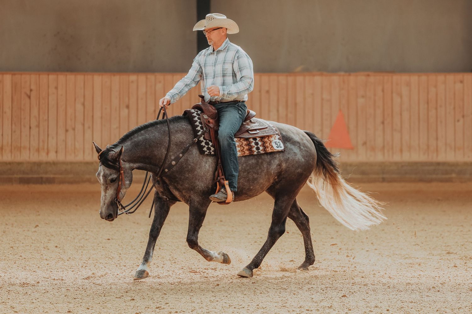Horse and rider execute western riding movements on dark horse with flowing tail.