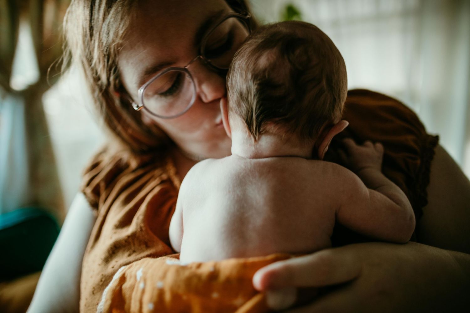 queer midwife and new parent kisses newborn home newborn photography portland oregon