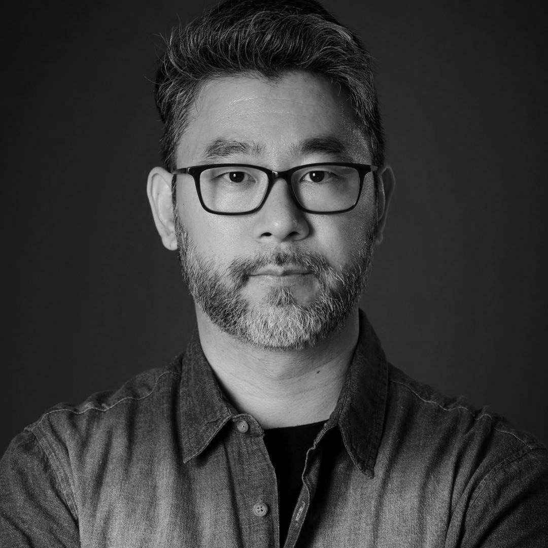 Professional studio portrait of an Asian man with glasses in black and white.