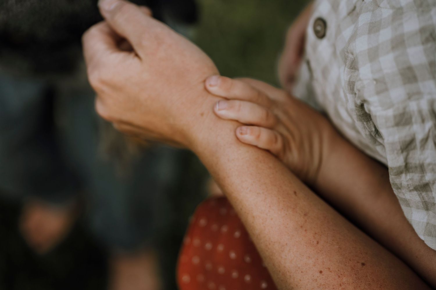 Close-up of hands gently touching during a tender family moment.