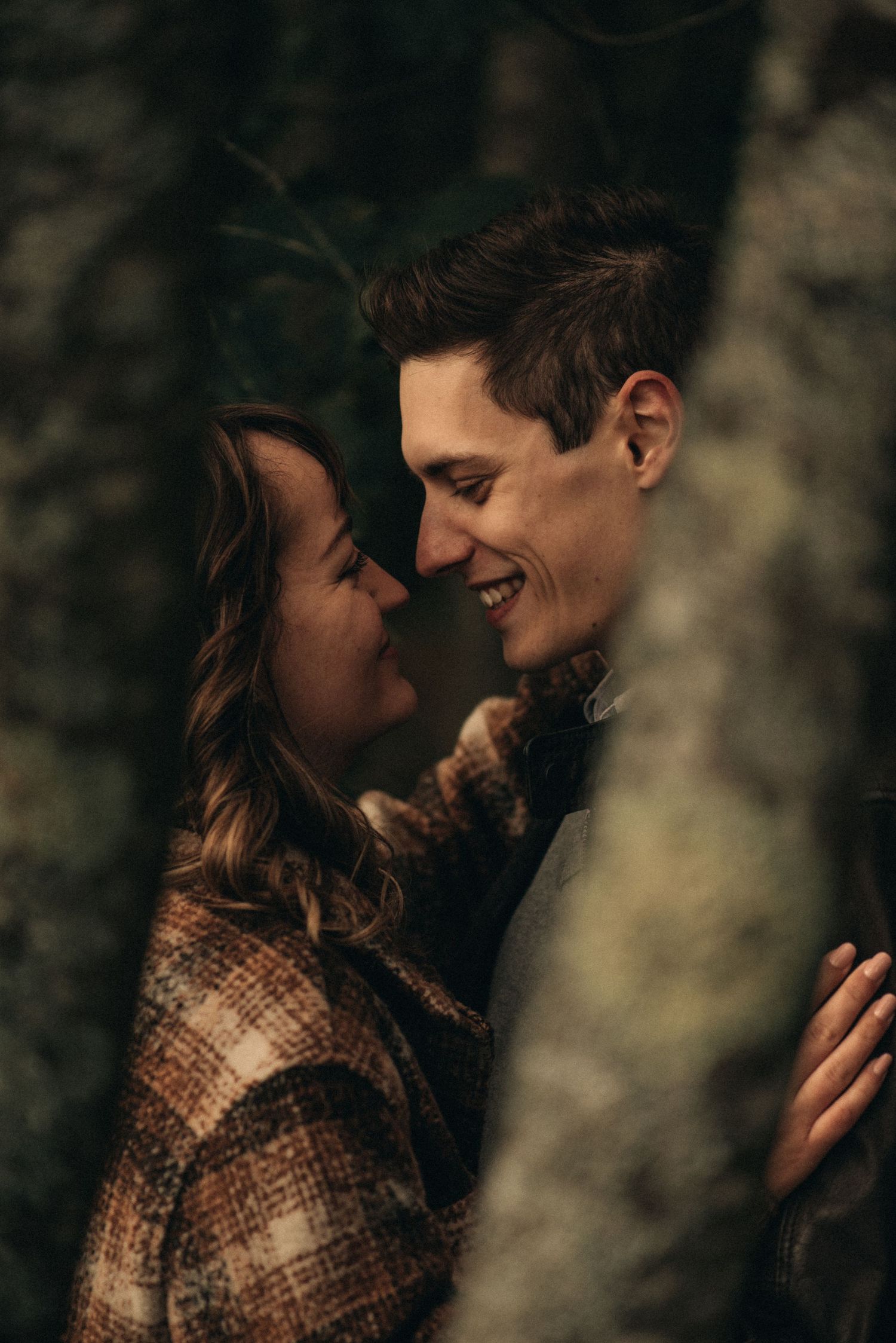Intimate moment shared between couple wearing autumn clothing against dark background.