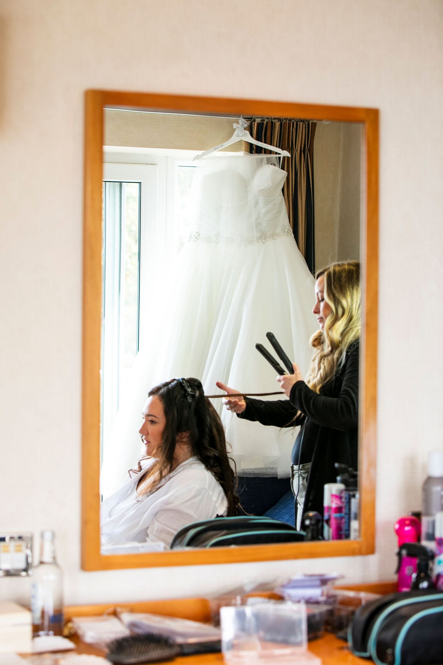 Getting ready scene in a dressing room with a large mirror and natural lighting.