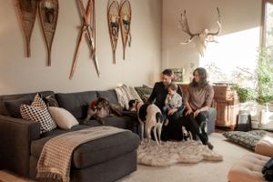 Family relaxing on sectional couch with vintage snowshoes and antlers displayed on wall.