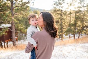 Tender outdoor family moment captured in snowy mountain landscape.