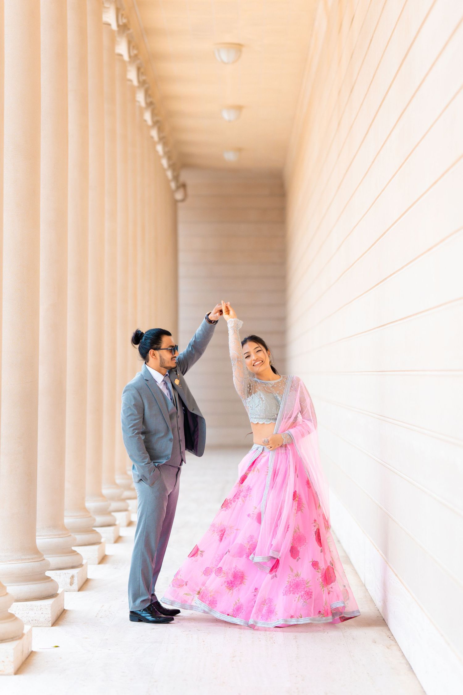 A joyful dancing moment captured between a couple in an elegant colonnade.