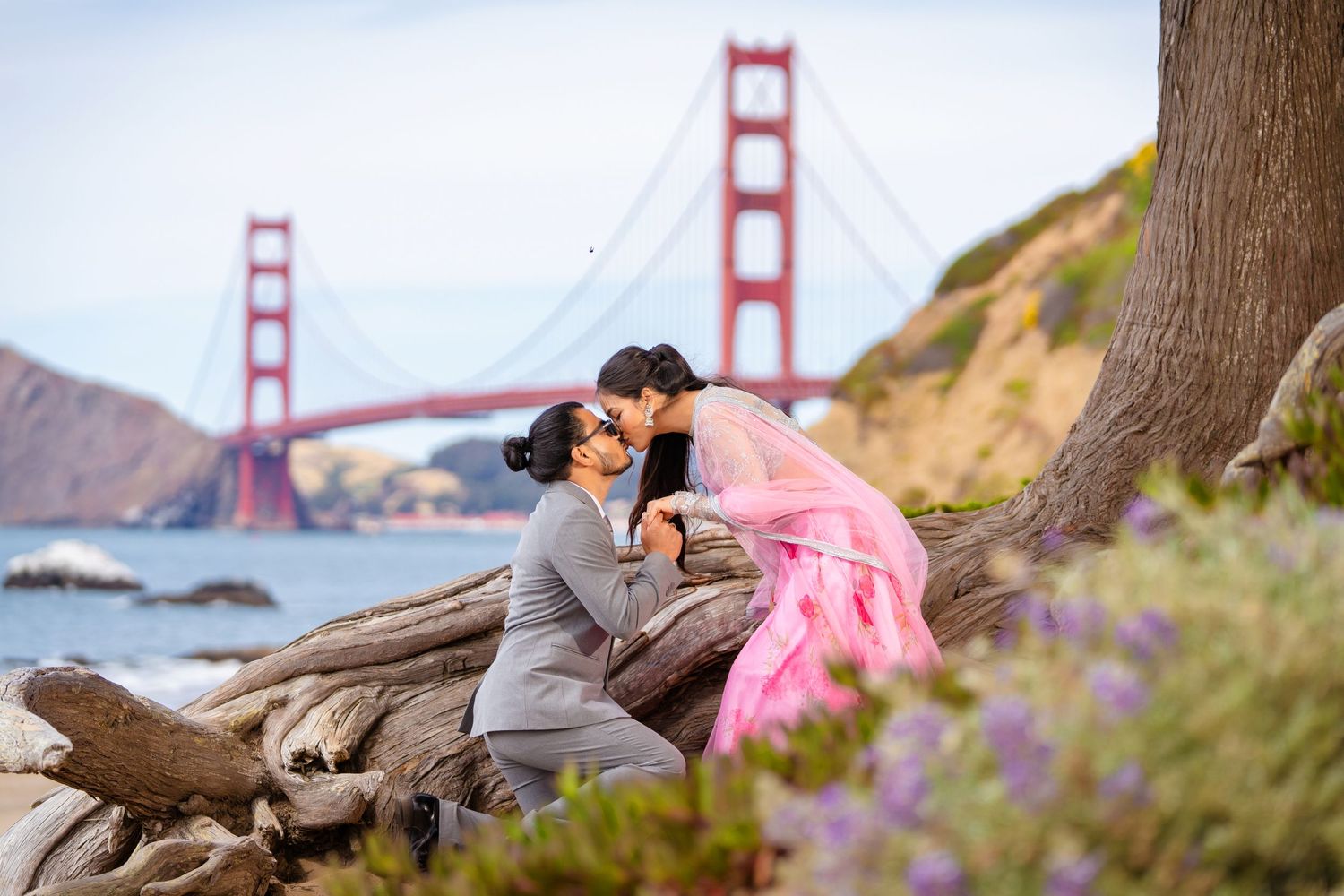 A sweet candid moment shared between a couple by the Golden Gate Bridge.