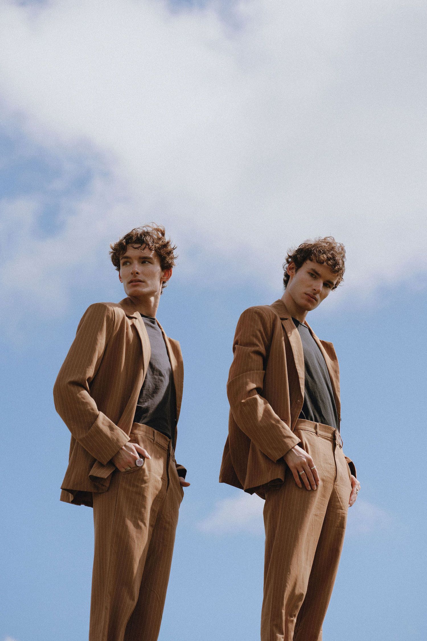 Two identical looks featuring tan suits and blazers photographed against a bright blue sky.