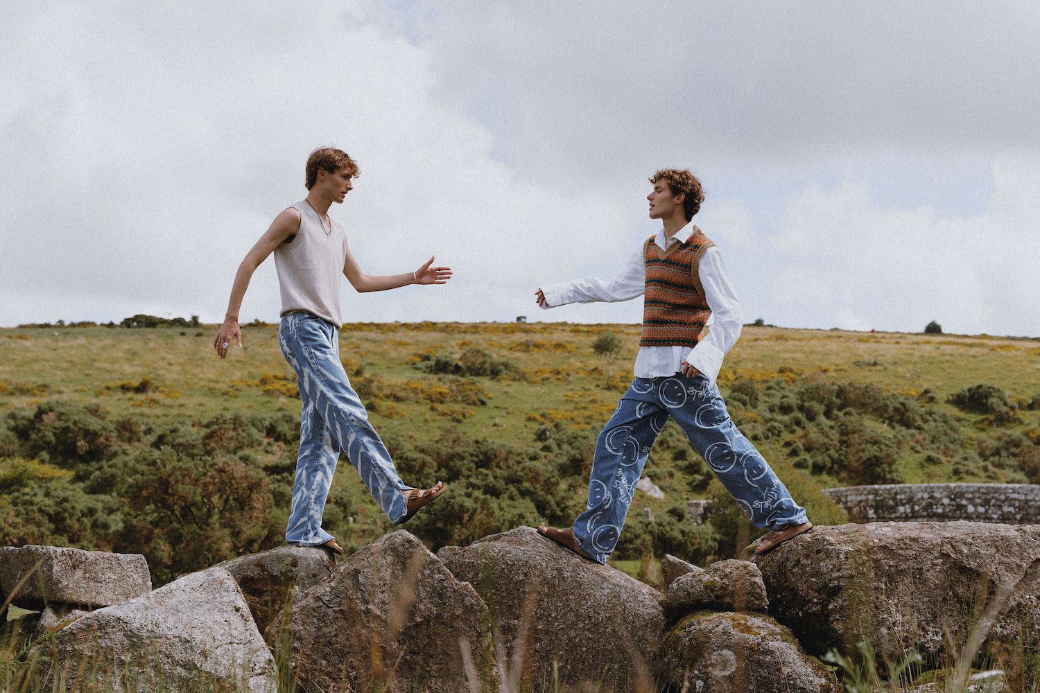 Two people carefully balance while walking on rocks in a natural outdoor setting.