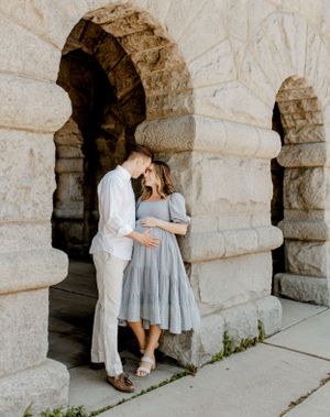 Intimate moment between couple against stone archway architecture.