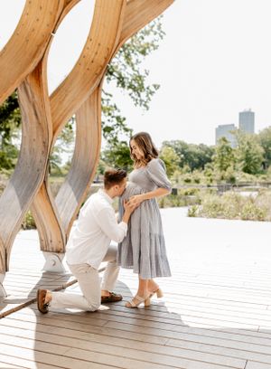 Romantic proposal moment under wooden archway in park with city skyline.
