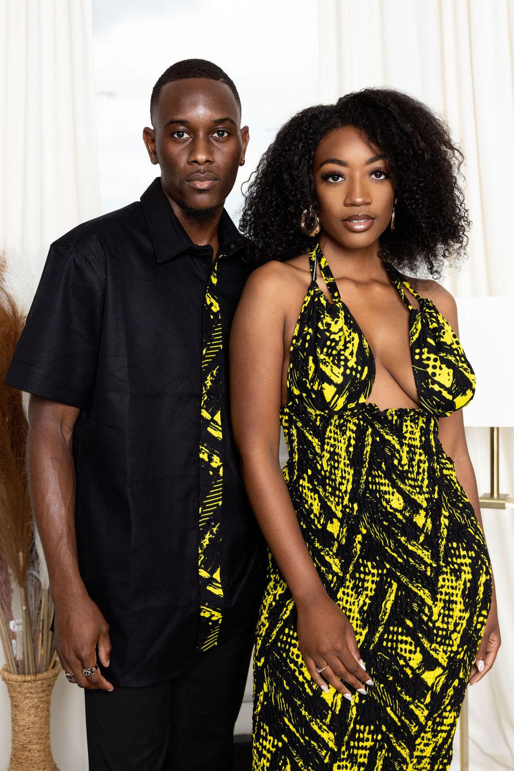 Fashion photoshoot with black and yellow outfits against white studio backdrop.