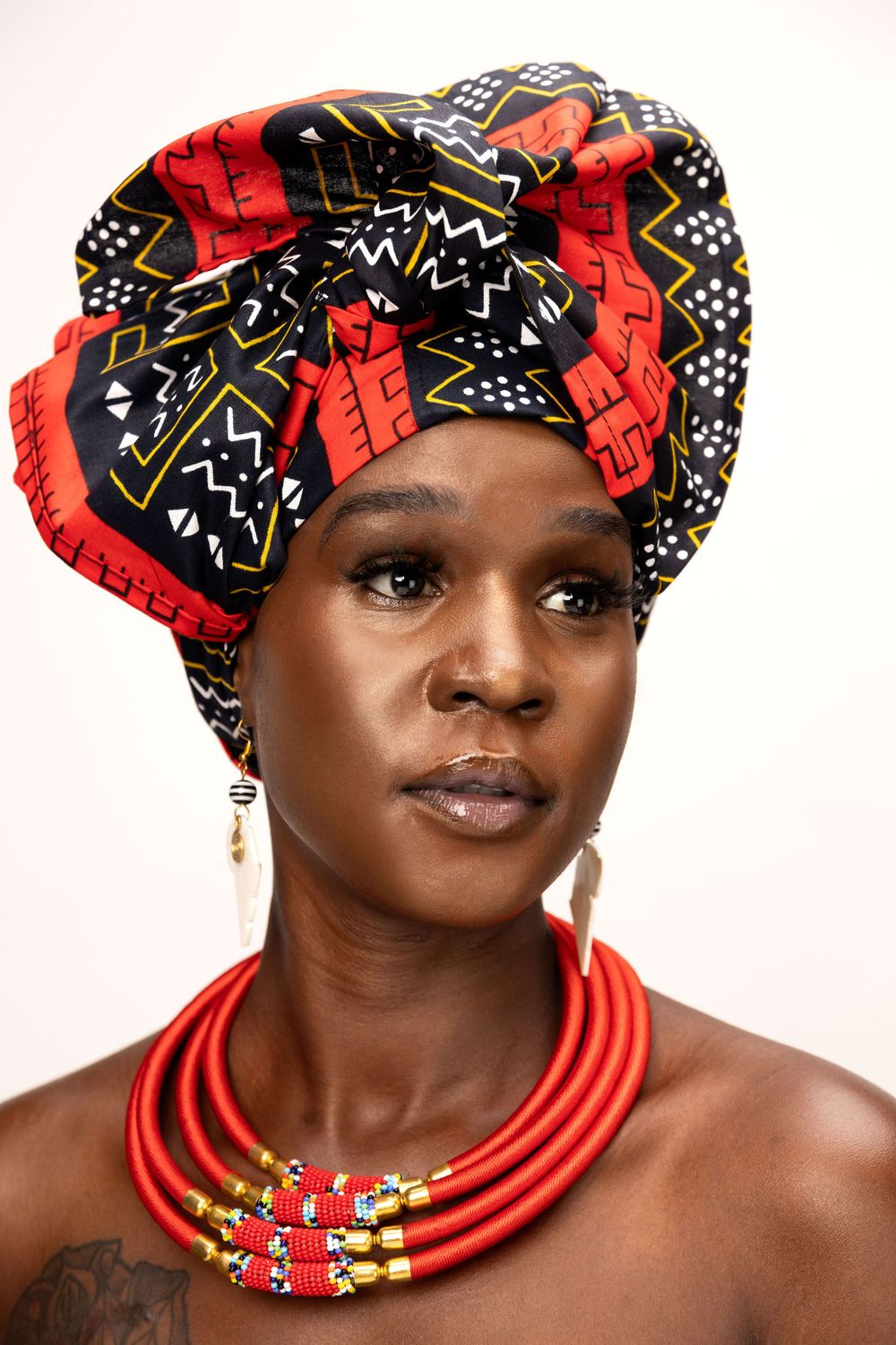Portrait series featuring traditional African headwrap and red beaded necklace against white background.