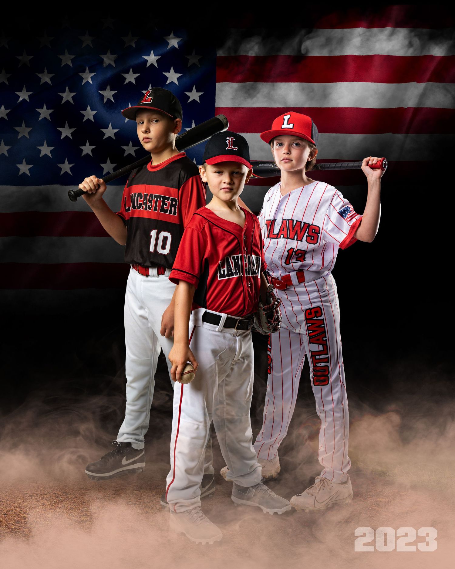 Youth baseball team players pose in uniforms with dramatic smoke effect and American flag background.