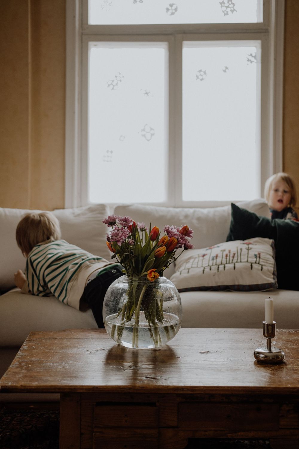 Cozy living room with fresh flowers in vase on wooden table near window.