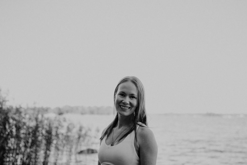 Black and white portrait of woman smiling by waterfront.