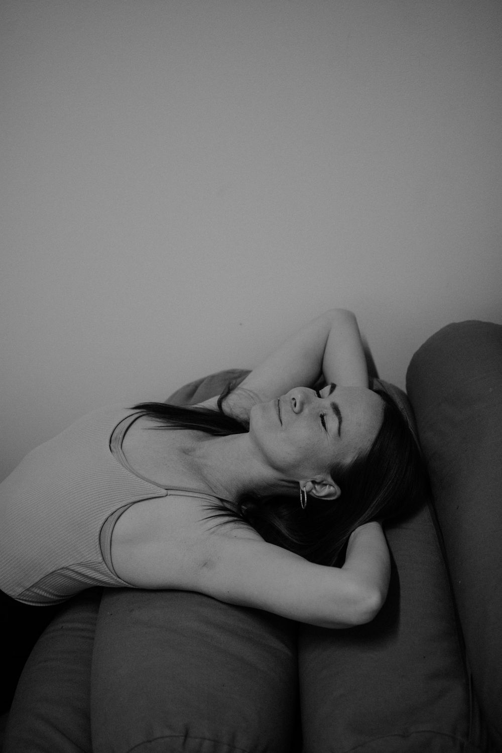 Person lying on couch in black and white photography creating peaceful mood.