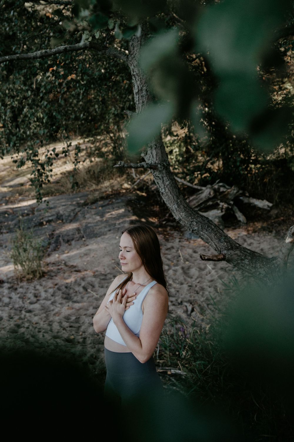 Woman in casual attire meditating in nature with soft lighting.