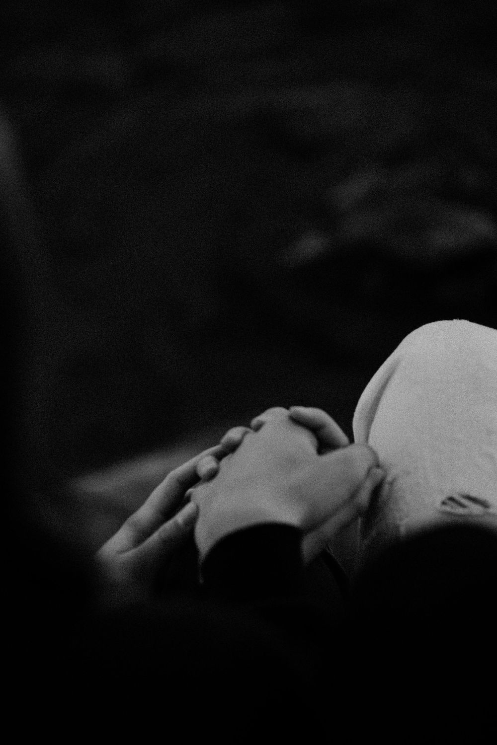 Gentle hands holding a white surface in black and white photography.