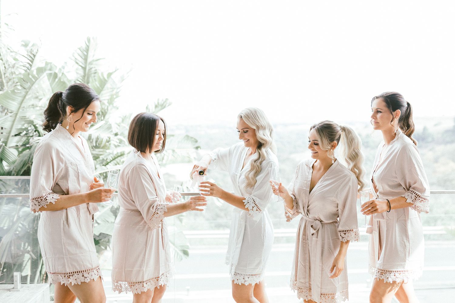 Group wearing matching silk robes celebrating with champagne and laughter.