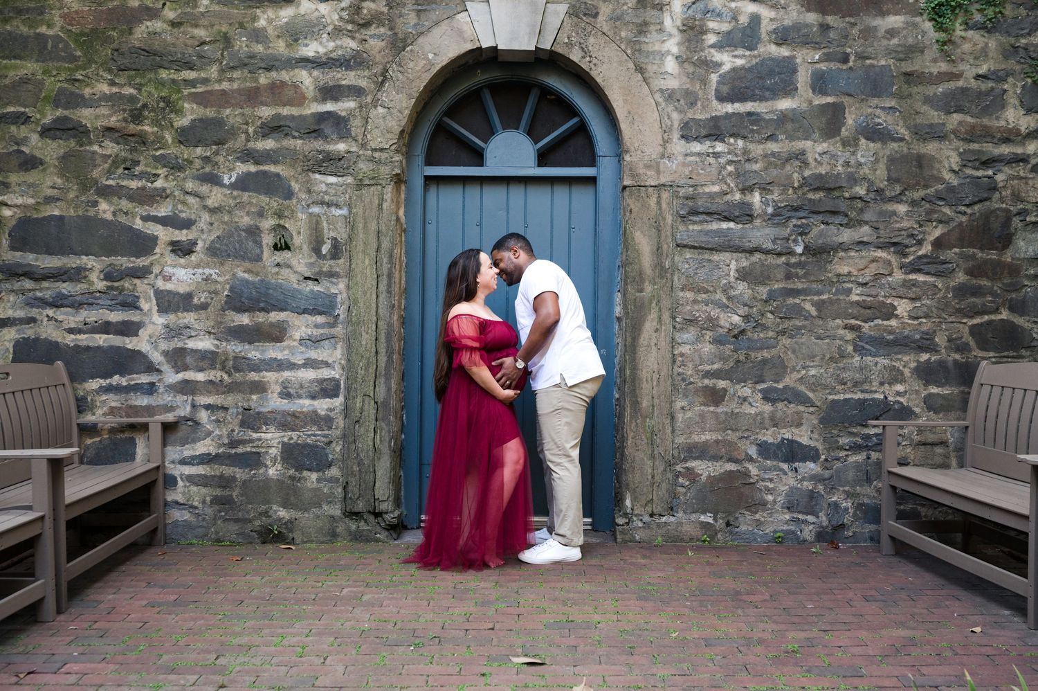 Couple posing in front of blue church door with stone wall background.